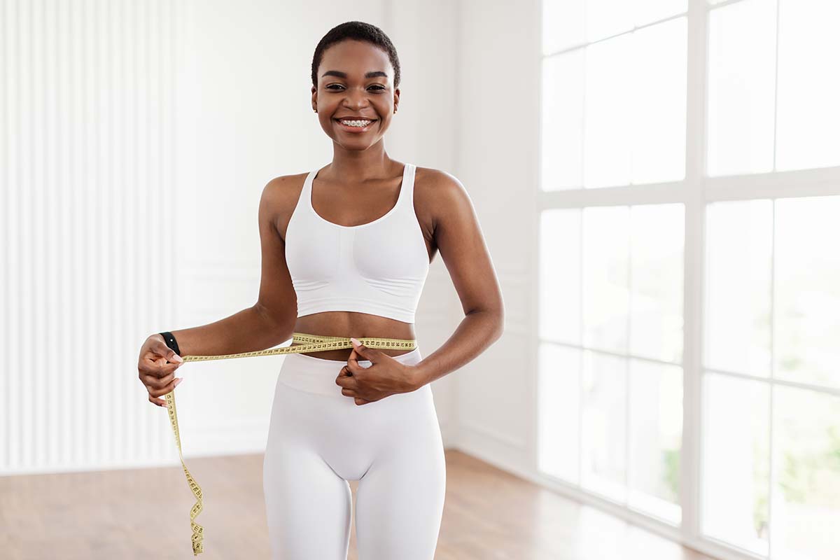 Happy Black Woman Measuring Waist With Tape. Slimming Concept